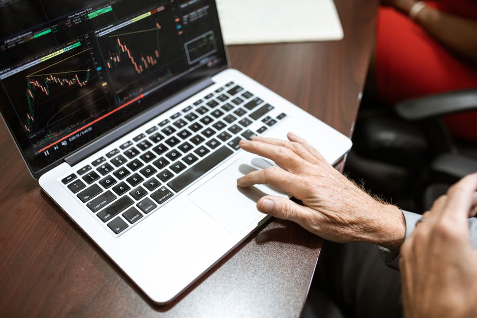 Organic traffic for affiliate offers — Close-up of hand using laptop for stock market analysis in office setting.