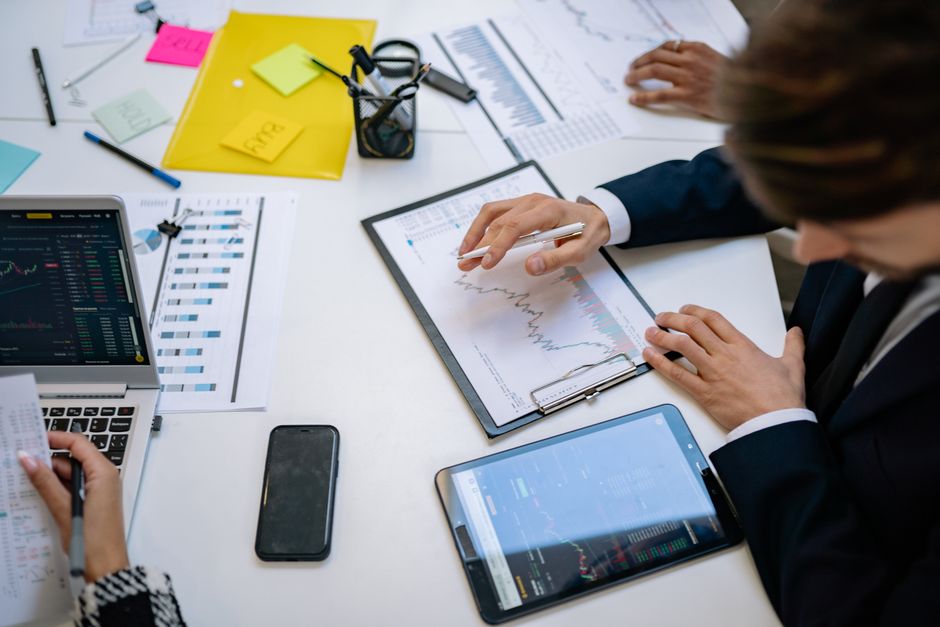 Profitable niche blog — Team reviewing financial charts and digital data on tablets in an office setting.