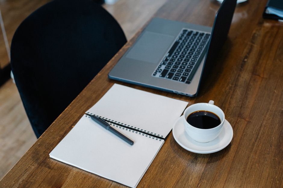 Profitable paid newsletter — High angle of opened laptop and spiral notebook with blank pages placed on wooden table with