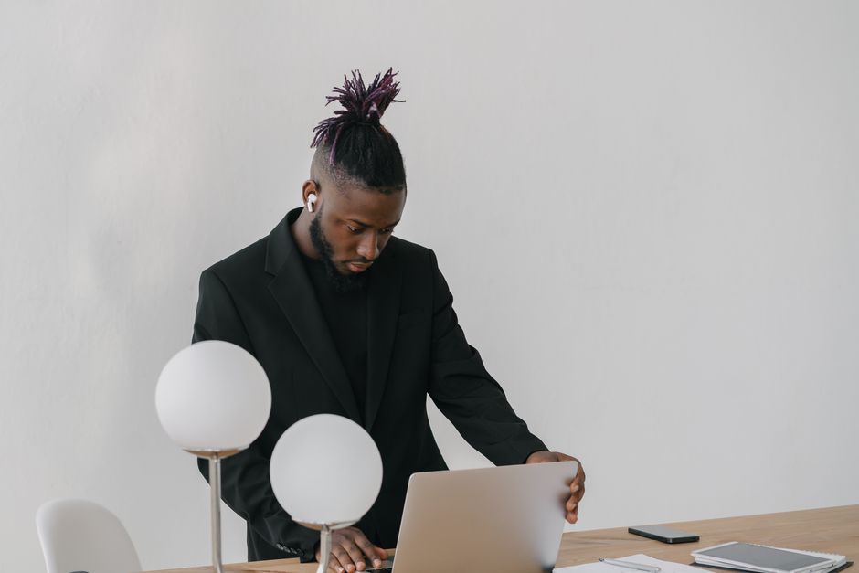 Solopreneur tech stack review — A focused black businessman in business attire working remotely on a laptop in an office