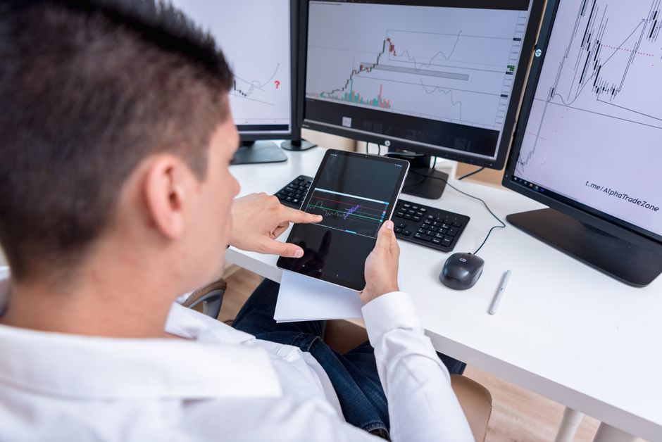 Winning dropshipping products — A stock trader analyzing cryptocurrency charts on multiple monitors and a tablet.